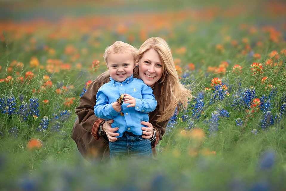 Grandmother and toddler smiling together in Texas bluebonnets during Houston Bluebonnet Mini Sessions, surrounded by spring wildflowers